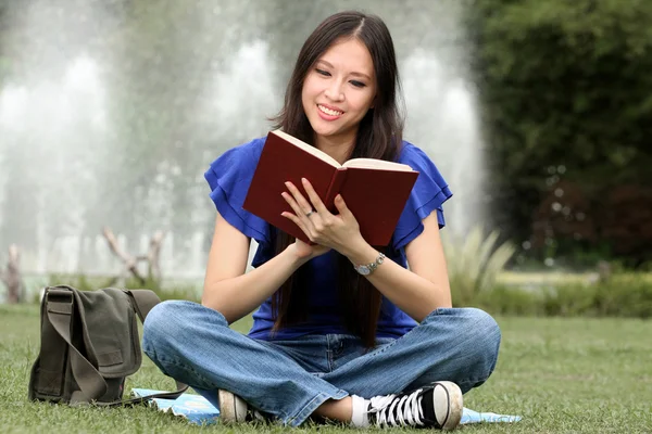 Hübsche junge Frau liest im Park ein Buch — Stockfoto