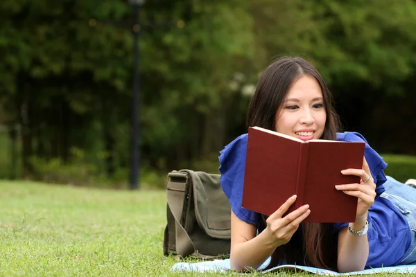 Hübsche junge Frau liest im Park ein Buch — Stockfoto
