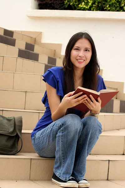 Hezká mladá žena čte knihu na schodiště — Stock fotografie
