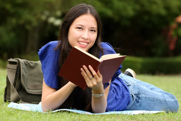 Hübsche junge Frau liest im Park ein Buch — Stockfoto