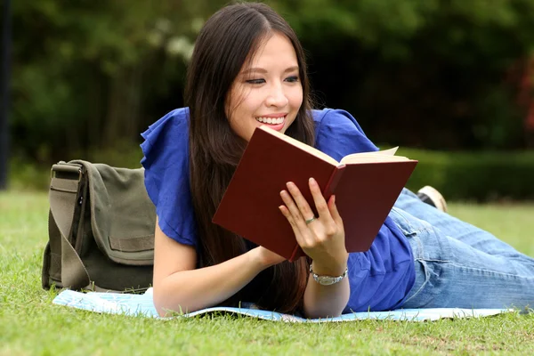 Hübsche junge Frau liest im Park ein Buch — Stockfoto