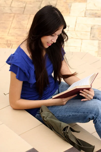 Hübsche junge Frau liest im Treppenhaus ein Buch — Stockfoto