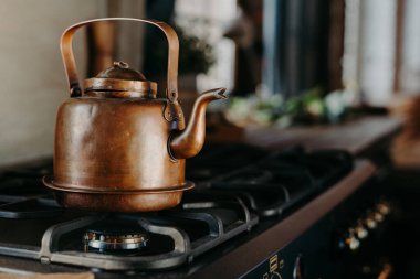 Modern mutfakta bronz çaydanlık. Gaz sobasında eski bir çaydanlık. Çay hazırlıyorum. Alüminyum çaydanlık. Pencereden güneşli gün ışığı.