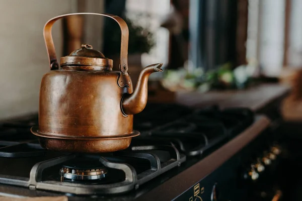 Hervidor de agua de bronce en la cocina moderna. Tetera antigua vintage en estufa de gas. Preparando té. Tetera de aluminio. Luz del día soleada desde la ventana. —  Fotos de Stock