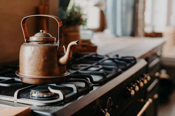 Hervidor de agua de aluminio viejo hervir en la cocina de gas contra el fondo borroso acogedor. Artículo antiguo hecho de metal de cobre. Estilo vintage —  Fotos de Stock