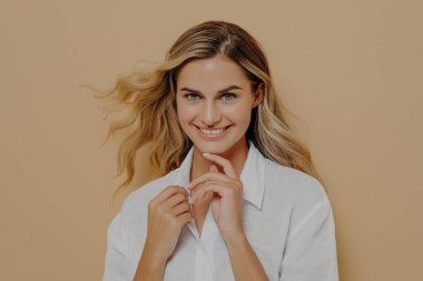 Flirty romantik ve kadınsı güzel sarışın kadın kameraya geniş gülüşlü bakıyor.