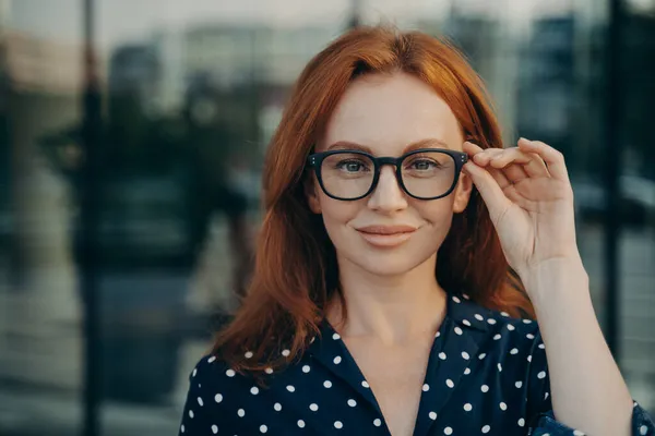 Självsäker vacker rödhårig affärskvinna justerar glasögon glasögon poserar på gatan — Stockfoto