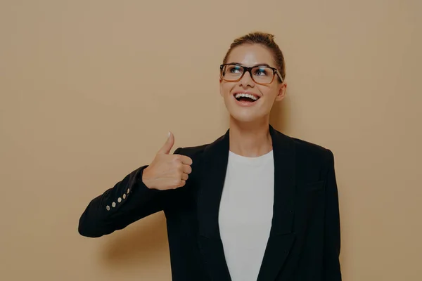 Porträtt av nöjd kvinna i glasögon leende samtidigt som tummen upp med handen — Stockfoto