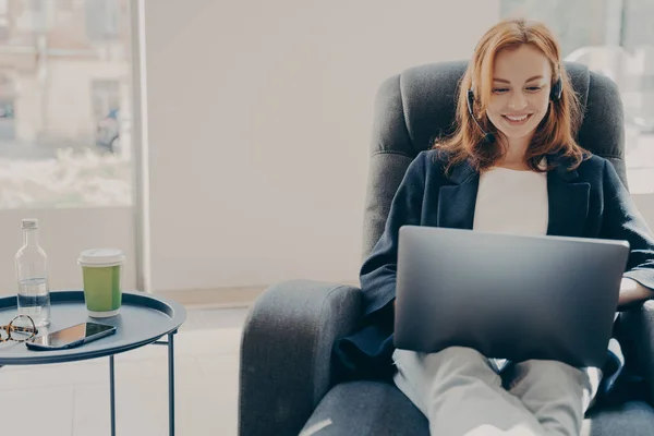 Glad leende kvinnlig frilansare under online-konferens via modern bärbar dator hemma — Stockfoto