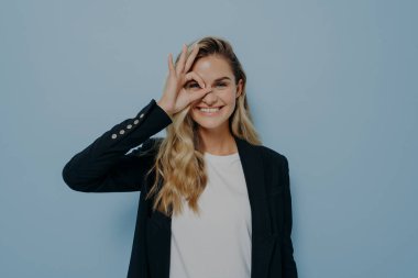 Uzun sarı saçlı, siyah ceketli, mutlu genç bir kadının el hareketlerini tasvir ediyorum.