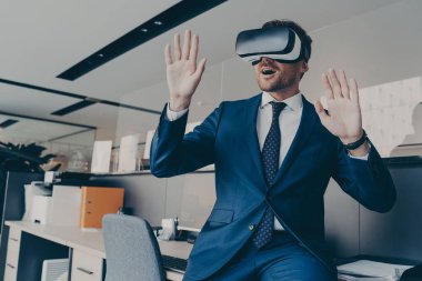 VR kulaklıklı CEO ofiste otururken sanal nesnelerle ya da arayüzle etkileşime giriyor