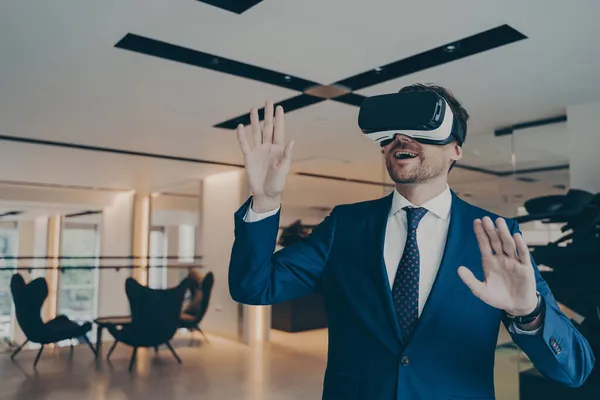 Empresário em headset VR futurista toca ar com as palmas das mãos imersas em realidade virtual — Fotografia de Stock