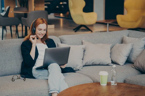 Positiva kvinnliga studerande som utför deltidsarbete arbetar på distans med bärbar dator och trådlöst headset — Stockfoto