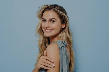 Mutlu, mutlu, gülümseyen sarışın kadın omzunun üstünden bakıyor.