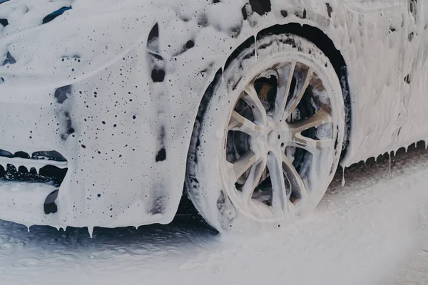 Auto kolo v bílé mýdlové pěně na mytí aut servisní stanice — Stock fotografie