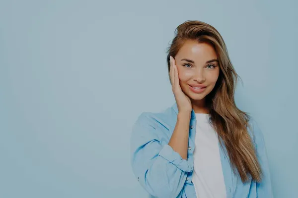 Mulher positiva sorrindo para a câmera no fundo azul claro — Fotografia de Stock