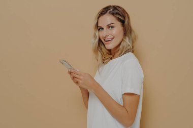 Sosyal ağının haber kaynaklarını kontrol ederken kameraya bakarak cep telefonu kullanan sevimli kız öğrenci.