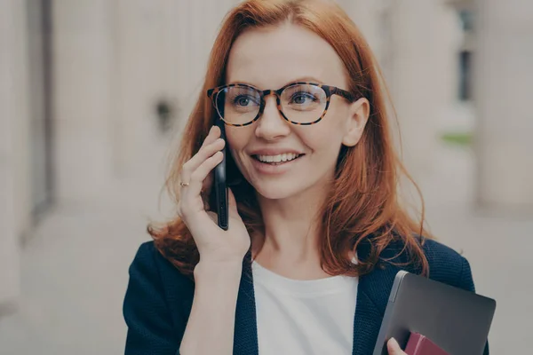 パートナーと呼ばれる眼鏡をかけた積極的な赤髪のビジネス女性を笑顔、屋外に立つ — ストック写真