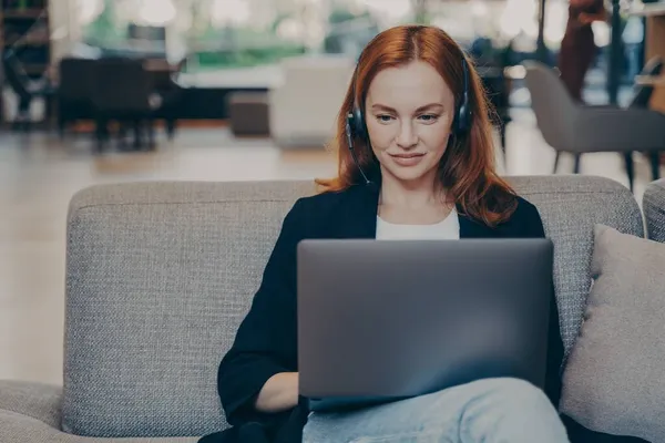 Confident smiling businesswoman using headset earphones and laptop, working remotely online — Stock Photo, Image