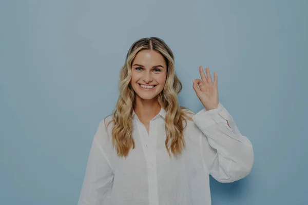 Glädjande blond kvinna gör ok gest med handen — Stockfoto