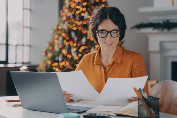 Gülümseyen İspanyol kadın çalışan Noel zamanı ofiste çalışıyor.