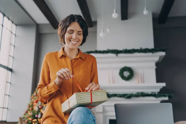 Ευτυχισμένη νεαρή Ισπανίδα που ασχολείται με τη συσκευασία χριστουγεννιάτικα δώρα στο σπίτι κατά τη διάρκεια των διακοπών των Χριστουγέννων — Φωτογραφία Αρχείου