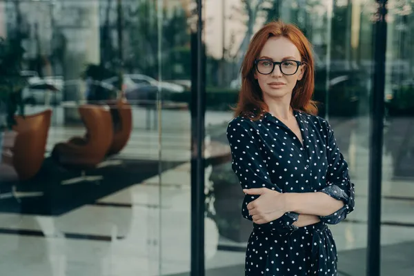 자신있는 여성 감독붉은 머리를 하고 사무실 건물 근처에 포즈를 취하다 — 스톡 사진