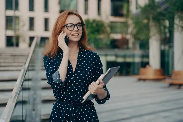 Rousse positive femme européenne a une conversation téléphonique tout en marchant en plein air — Photo