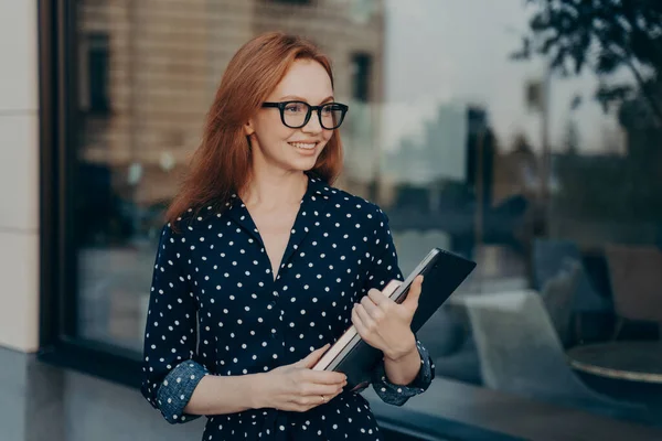 Femme d'affaires avec les cheveux roux porte dispositif moderne et bloc-notes va sur réunion formelle — Photo