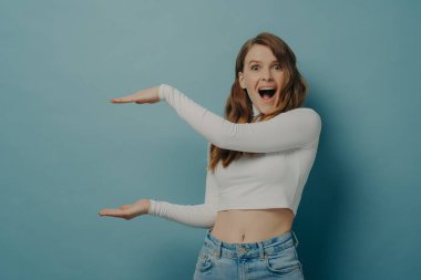 Elleri büyük ve büyük ölçü sembolü olan, mavi üzerine izole edilmiş, şok olmuş bir kadın.