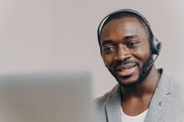 Молодой обрадованный африканский мужчина звонит агенту колл-центра, разговаривает с клиентом, консультирует клиента онлайн — стоковое фото