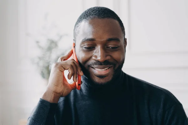 Mladý usmívající se africký muž s obchodní konverzaci na mobilním telefonu — Stock fotografie