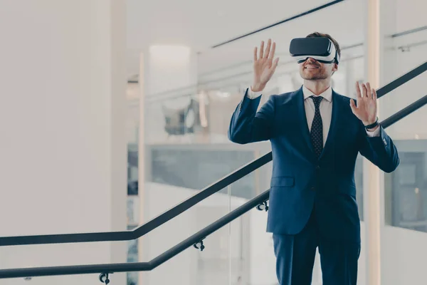 Εντυπωσιασμένος άνδρας υπάλληλος γραφείου που φοράει γυαλιά εικονικής πραγματικότητας εξερευνώντας τον εικονικό κόσμο ενώ βρίσκεται στο γραφείο — Φωτογραφία Αρχείου