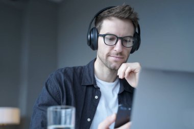 İşyerinde cep telefonu dinleyerek kablosuz kulaklık takan genç bir Alman.