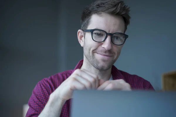 Sorridente giovane tedesco freelance in occhiali che lavora in remoto online sul computer portatile da casa ufficio — Foto Stock