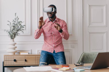VR kulaklıklı Afrikalı adam dijital arayüzle etkileşimde, iş için yenilikçi bir cihaz kullanıyor