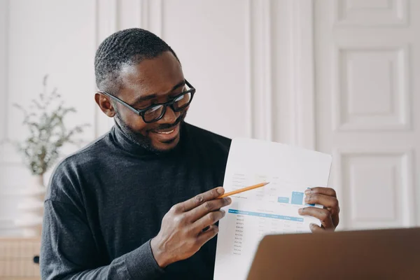Молодой улыбающийся африканский бизнесмен объясняет финансовый отчет во время онлайн-встречи — стоковое фото