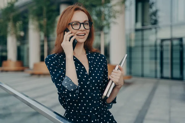 Ruiva alegre mulher europeia fala no telefone móvel moderno tem boa expressão — Fotografia de Stock