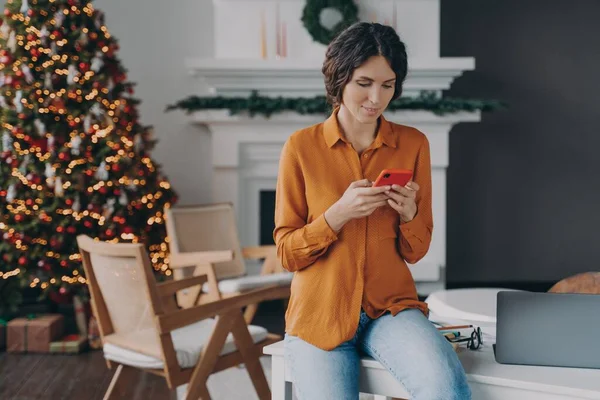 크리스마스 휴일에 현대의 스마트폰을 사용하여 집에서 일하는 매력적 인 이탈리아 사업가 — 스톡 사진