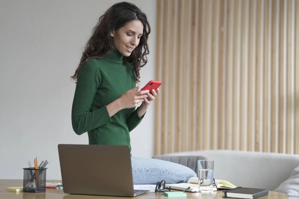 Joven mujer italiana feliz freelancer utilizando la aplicación móvil en su lugar de trabajo en casa — Foto de Stock