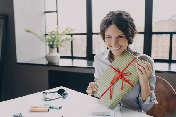 Alegre empleada de oficina dama mirando pantalla ampliamente sonriente mostrando a la cámara de la computadora regalo de Navidad —  Fotos de Stock