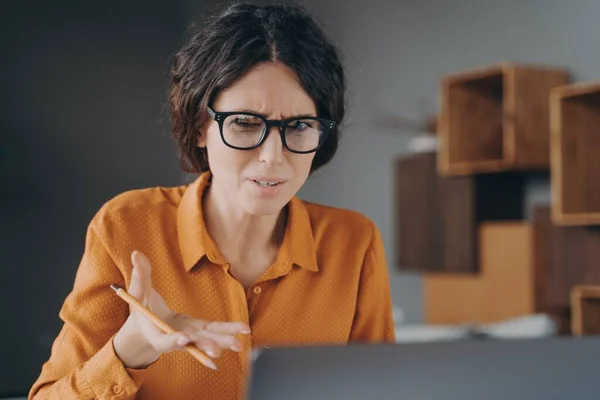 Freelancer española frustrada que se ve enojada en la pantalla del ordenador portátil mientras trabaja desde casa —  Fotos de Stock