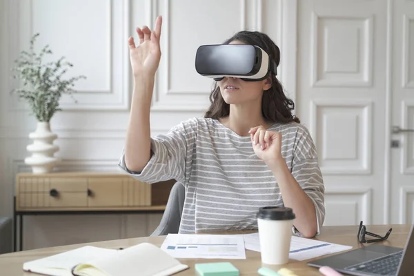 Mujer joven enfocada que usa auriculares de realidad virtual viendo contenido de 360 grados en el trabajo — Foto de Stock