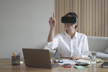 VR kulaklıklı kadın ofis çalışanı dijital arayüzle etkileşimde, 3D nesnelere dokunuyor