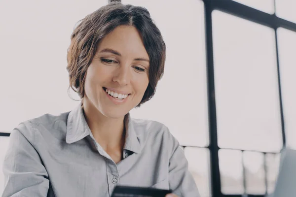 Mujer de negocios sonriente con tarjeta de crédito utilizando el sistema de pago en el trabajo —  Fotos de Stock