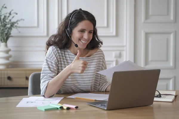 Atractiva mujer de negocios agradable con auriculares con micrófono que muestra el pulgar hacia arriba —  Fotos de Stock