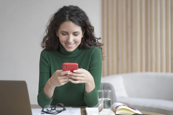검은 수염을 가진 젊은 이탈리아 프리랜서 여성 이 핸드폰을 들고 웃으며 스크린을 바라본다 — 스톡 사진