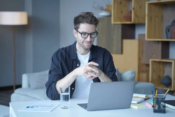 Jeune bel homme allemand portant des lunettes de travail sur ordinateur portable à distance de la maison — Photo