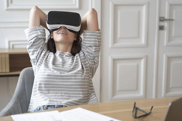 Joven empleada feliz en gafas VR en el lugar de trabajo viendo películas — Foto de Stock