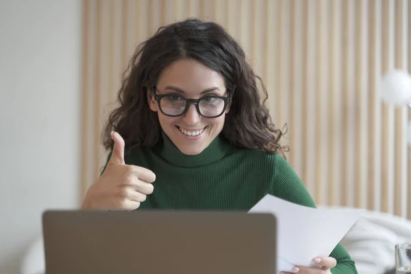 Feliz joven empleado italiano habla en línea en el ordenador portátil con sus colegas y mostrando el pulgar hacia arriba —  Fotos de Stock